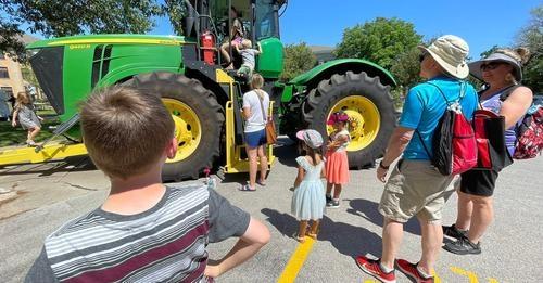Group of people gathred around a tractor at East Campus Discovery Days and Farmer's Market